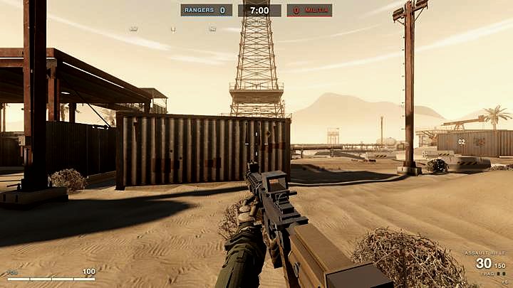 A derrick tower over a desert oilfield seen down a rifle